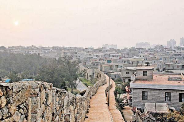 在崇武古城牆上賞日落,夕陽紅霞映入古城與民居。 泉州